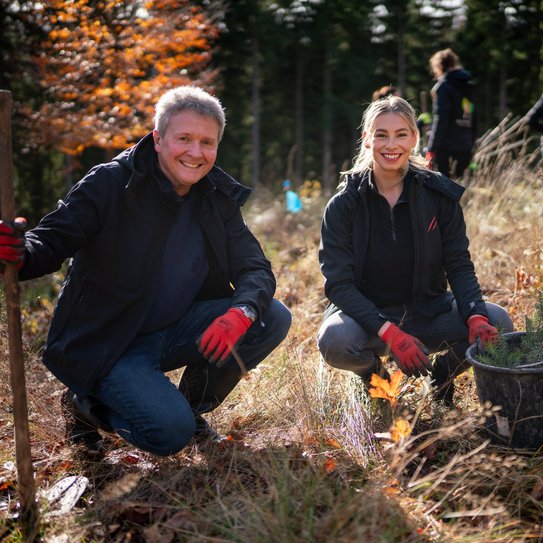 Zwei Personen knieend in einem Waldgebiet