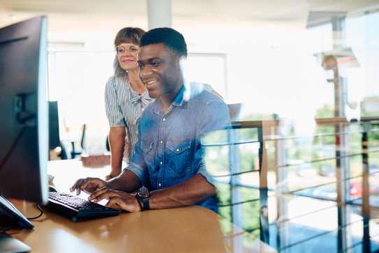 Zwei Mitarbeitendearbeiten gemeinsam an einem Desktop-Computer.